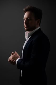 a man in a black suit and white shirt is holding his hands out to the side