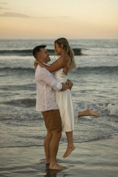 a man carrying a woman on his back while standing in the water at sunset near the beach