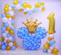 a balloon arch decorated with balloons and a gold crown for an infant's first birthday