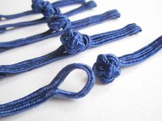 four pieces of blue rope with flowers on them are laid side by side in the shape of roses