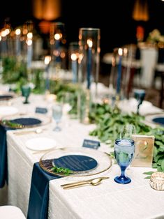 the table is set with blue and white plates, silverware, and greenery