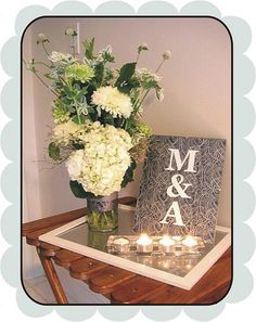 a vase with flowers and candles on a small table in front of a card holder