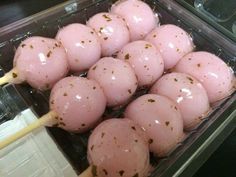 several pink donuts with sprinkles on them in a plastic container, ready to be eaten