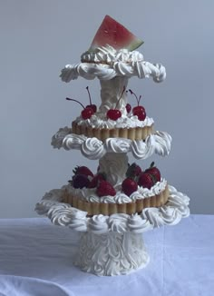 a three tiered cake with white icing and fruit on top, sitting on a table