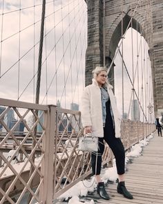 an older woman standing on the side of a bridge with her hand in her pocket