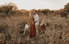 a man and woman are standing in the middle of a field with their two children