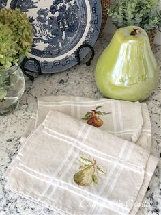 two tea towels on top of a counter next to some vases and other decorative items