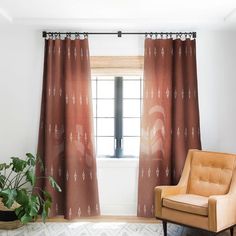 an orange chair sitting in front of a window next to a potted green plant