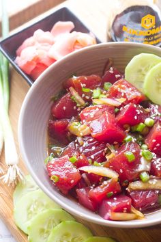 a white bowl filled with food next to sliced cucumbers and celery