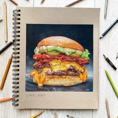 a drawing of a cheeseburger with bacon and lettuce on it, surrounded by colored pencils