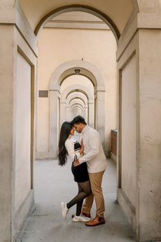 a man and woman are kissing in an archway between two buildings, one is holding the other's head