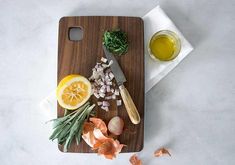 a cutting board with onions, lemons and herbs on it