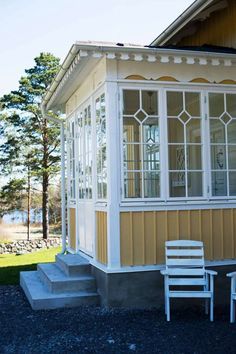 a yellow and white house with two chairs