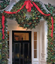 the front door is decorated for christmas with wreaths and red ribbons on it's sides