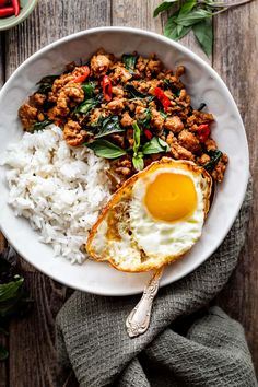 a bowl filled with rice, meat and an egg on top of it next to a spoon