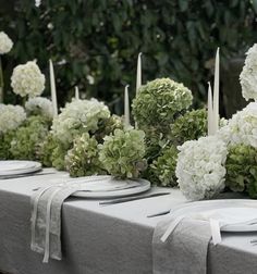 white flowers and greenery are arranged on the table for an outdoor wedding reception or special event