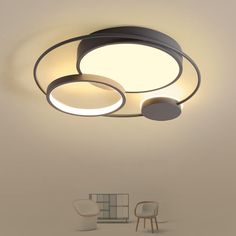 a ceiling light with two circular lights above it and a chair in the corner next to it