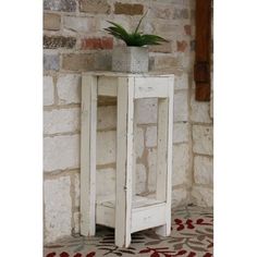 an old white cabinet with a potted plant on top is shown in front of a brick wall