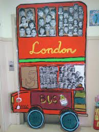 a red double decker bus sitting in front of a wall with pictures on the side