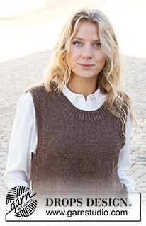 a woman wearing a brown sweater and white shirt standing in front of a cobblestone road