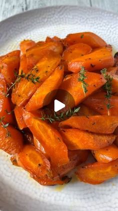 a white plate topped with sliced up carrots and garnished with parsley