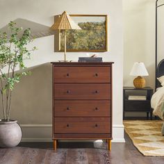 a bedroom scene with focus on the chest of drawers and a painting hanging above it