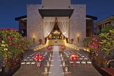 an outdoor wedding setup at night with flowers and candles on the aisle, surrounded by potted plants