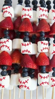 strawberries and blueberries are arranged on skewers with baseball pinstripes