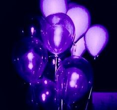 a bunch of purple balloons in a glass vase