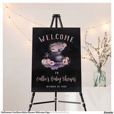 a welcome sign for a baby shower is displayed on an easel with lights in the background