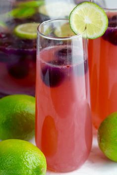 two glasses filled with sangria next to limes