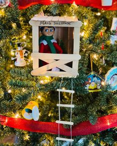 an ornament hanging from the top of a christmas tree with red ribbon around it