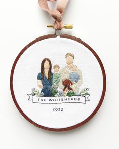 a cross stitch ornament hanging on a white wall with a ribbon around it