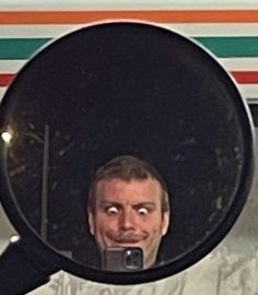 a man taking a selfie in the mirror of an airplane with his cell phone