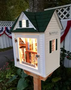 a white house with a green roof and lights in the windows is lit up at night