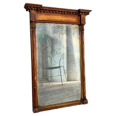 a chair sitting in front of a mirror on top of a wooden floor next to a potted plant