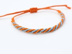 an orange and blue rope bracelet on a white background