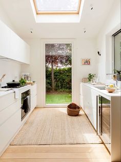 a kitchen with an open skylight above the sink and countertop, along with a rug on the floor