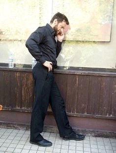 a man leaning against a wall with his hand on his face while talking on the phone