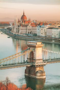 a bridge spanning over a river with buildings in the background