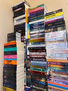 a large stack of books sitting on top of a white shelf next to a wall