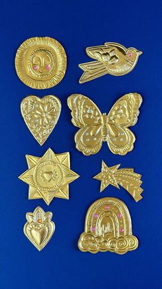 six different types of gold metal badges on a blue background, including one with pink eyes and the other with an eye