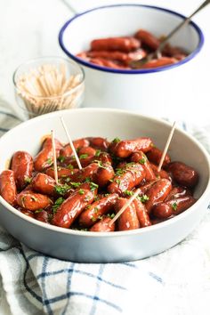 hot dogs with toothpicks in a bowl on a table next to other food