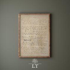 an old letter is hung on the wall above a table with a vase and potted plant