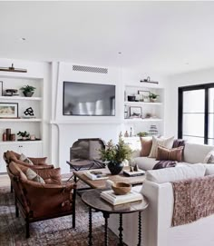 a living room filled with furniture and a flat screen tv mounted on the wall above a fire place