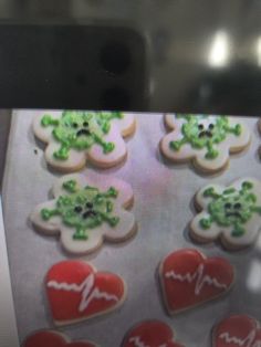 cookies decorated with green leaves and hearts are on a cookie sheet in front of a computer screen