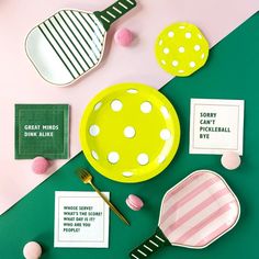 plates, spoons and candy on a table with pink and green decor around them