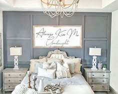 a large bed sitting under a chandelier next to a wall with writing on it