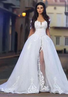 a woman in a white wedding dress standing on the street with her legs slited