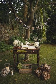 a table with pictures hanging from it in the grass next to a tree and other items